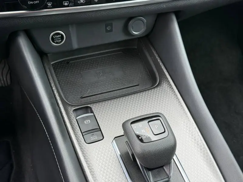 Gros plan sur la console centrale du Nissan Qashqai 2025, avec levier de vitesse automatique et finition gris texturé.
