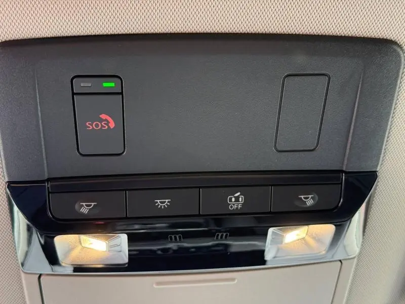Gros plan sur la console de plafonnier gris foncé du Nissan Qashqai 2025 avec boutons d’éclairage et alerte SOS allumée.