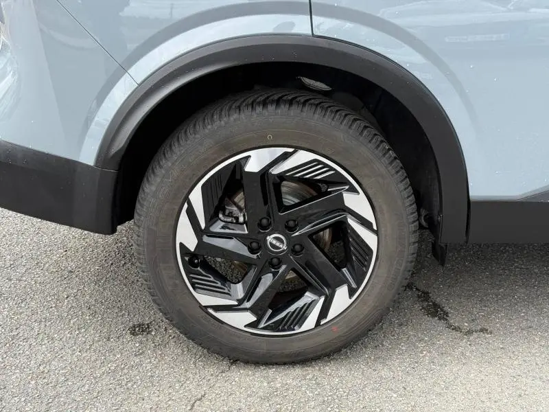 Gros plan sur la roue avant droite avec jante alliage noire et argent du Nissan Qashqai Gris Argile 2025.