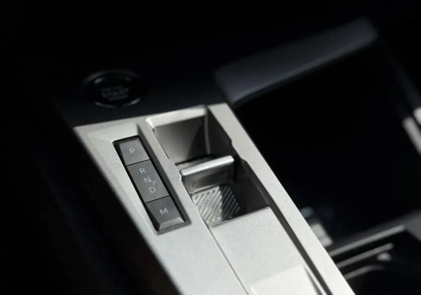 Gros plan sur la console centrale grise métallisée de la Peugeot 308 2025 avec boutons de boîte auto et rangement.