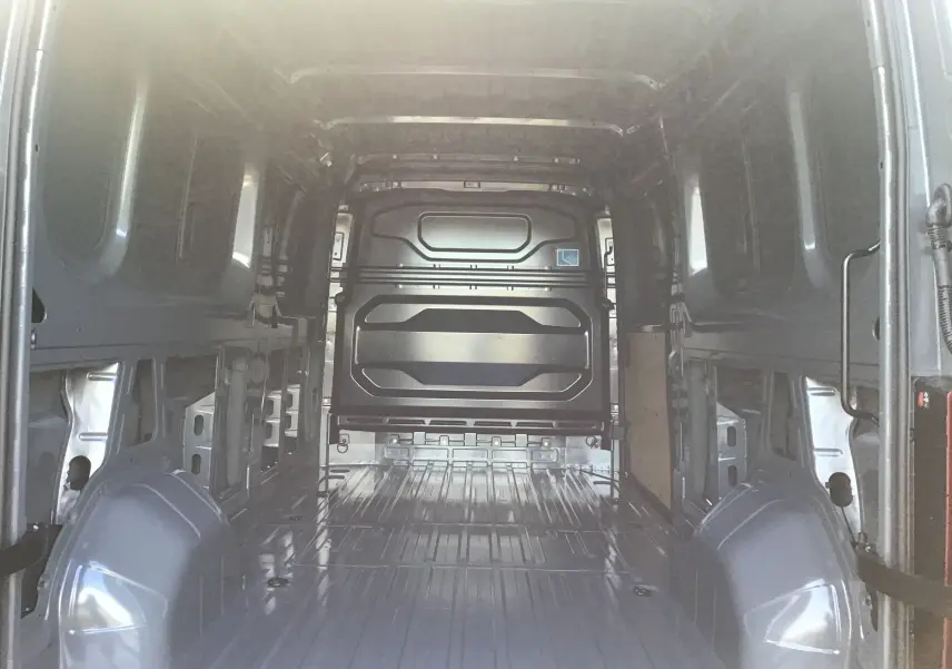 Vue intérieure arrière du Renault Master L3H2 gris urbain, montrant l'espace de chargement vide et la cloison métallique.