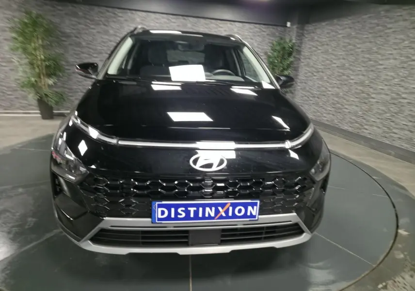 Vue avant d'un Hyundai Bayon noir 2025 avec calandre noire laquée et plaque Distinxion en intérieur showroom.
