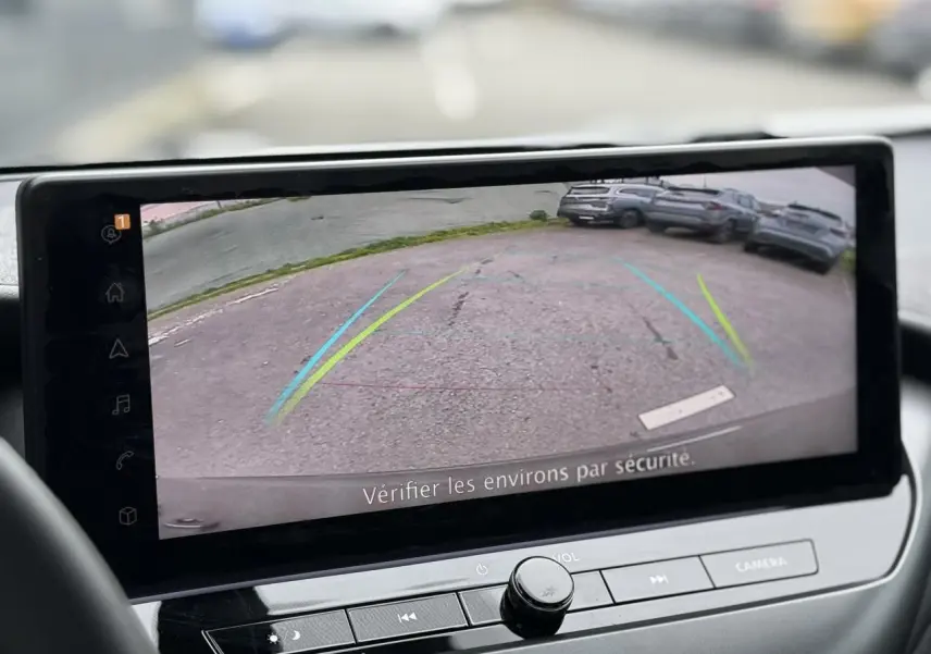 Écran tactile intérieur montrant la caméra de recul du Nissan Juke 2025, vue arrière sur un parking.