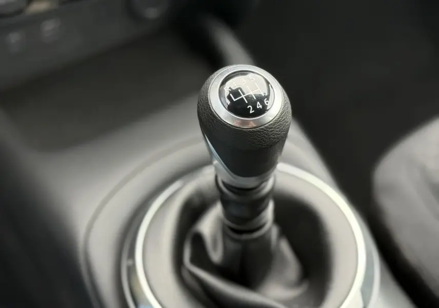 Gros plan sur le levier de vitesses manuel noir du Nissan Juke 2025, finition Acenta, intérieur sombre.