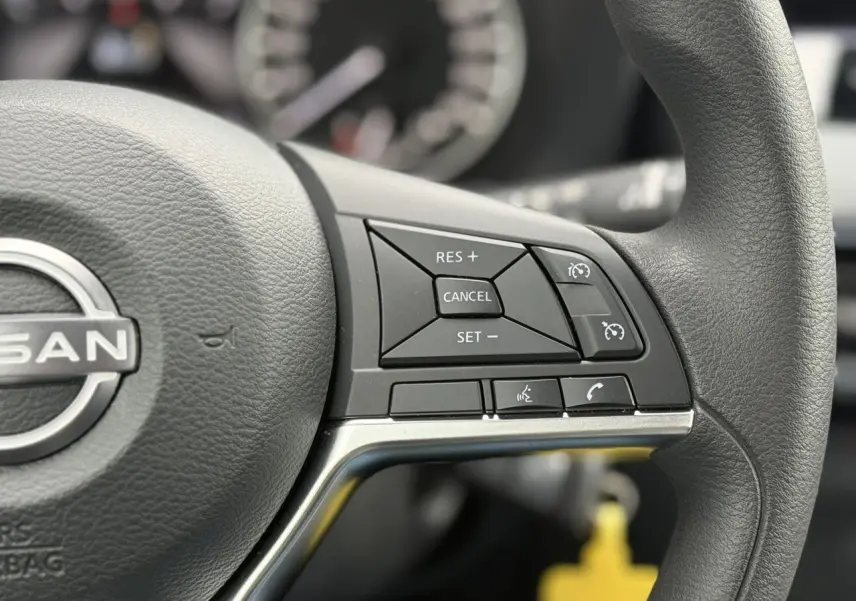 Gros plan sur le côté droit du volant noir du Nissan Juke 2025 avec commandes de régulateur et téléphone.