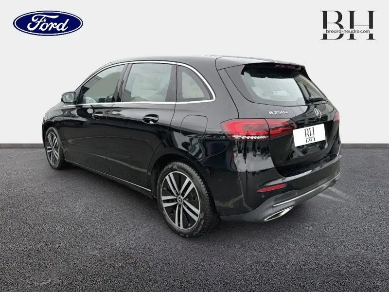 Vue 3/4 arrière droite d'une Mercedes Classe B 250 e noire cosmos métallisé avec hayon EASY-PACK et jantes alu.