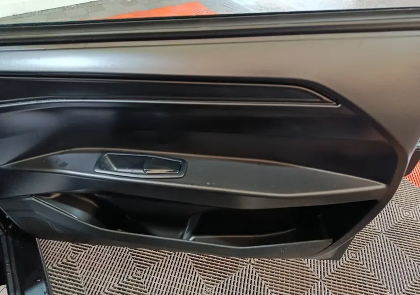 Intérieur montrant la porte côté conducteur de l'AIXAM Ambition 0.5 City Pack gris clair, avec poignée et rangement intégré.