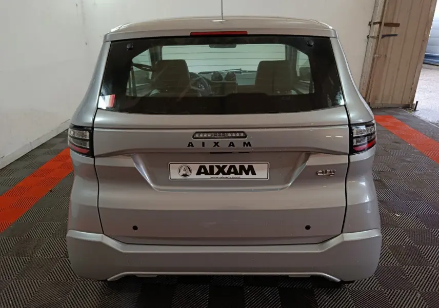 Vue arrière d'une Aixam Ambition 0.5 City Pack gris clair 2026 avec logo et feux arrière modernes.