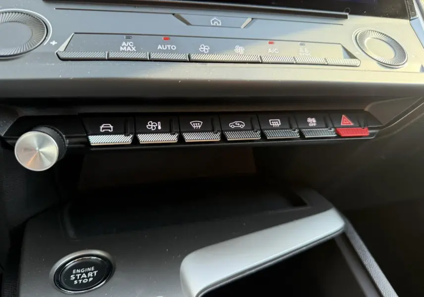 Vue rapprochée du tableau de bord de la Peugeot 308 2025, montrant les commandes climatisation et bouton start/stop.