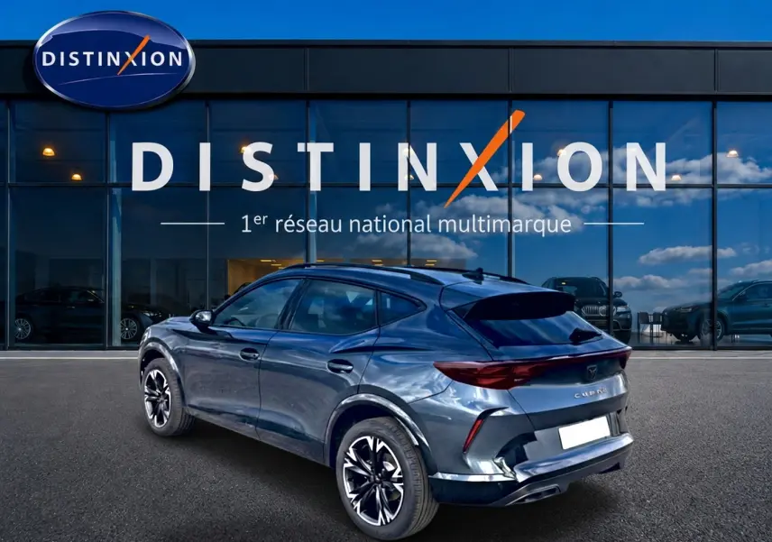 Vue 3/4 arrière droite d'un CUPRA Formentor gris magnétique avec jantes noires et toit plongeant devant un showroom Distinxion.