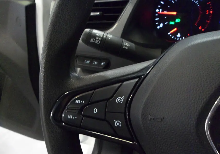 Gros plan sur le volant de Renault Kangoo 2022, montrant les commandes de régulateur de vitesse et le tableau de bord éclairé.