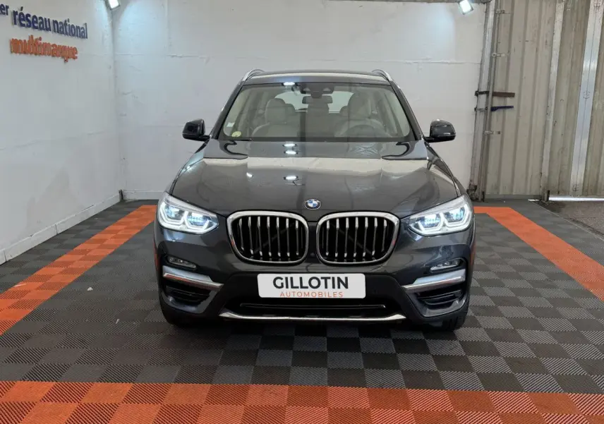 Vue frontale d'un BMW X3 gris foncé avec phares LED allumés et calandre double haricot caractéristique.