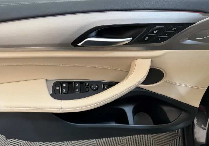 Poignée de porte côté gauche beige et noir de BMW X3 2018 avec commandes de vitres et verrouillage intégrées.
