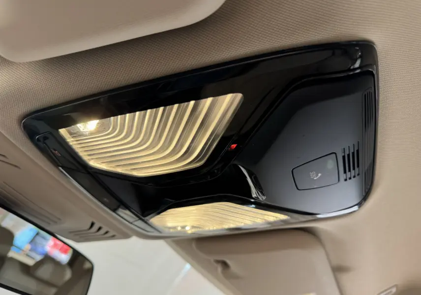 Plafonnier intérieur noir brillant avec éclairage LED et bouton SOS, vue en contre-plongée dans un BMW X3 gris foncé 2018.