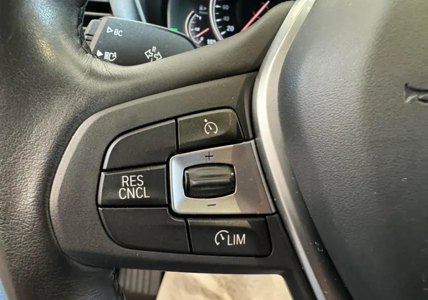 Gros plan sur les commandes de régulateur de vitesse au volant cuir noir du BMW X3 gris foncé 2018.