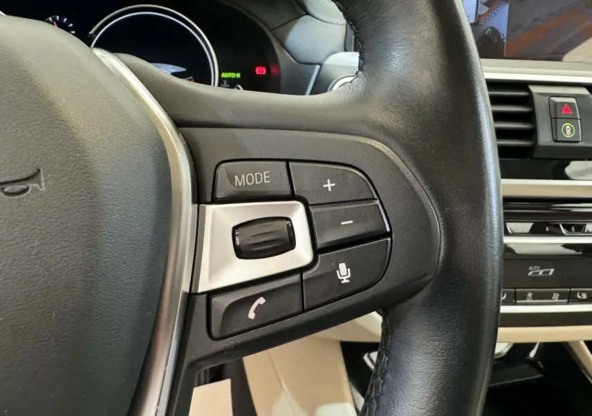 Gros plan sur le côté droit du volant en cuir noir du BMW X3 2018, avec commandes audio et vocales visibles.