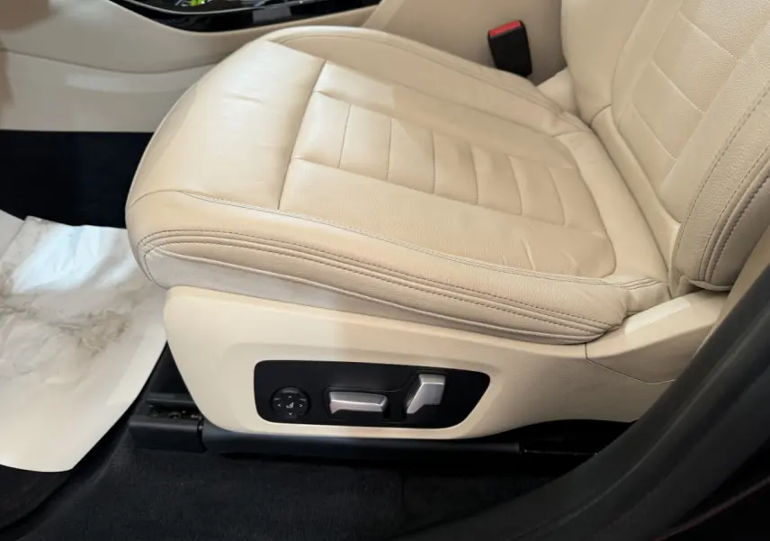 Gros plan sur le siège avant gauche en cuir beige clair avec commandes électriques d'ajustement sur BMW X3 gris foncé.