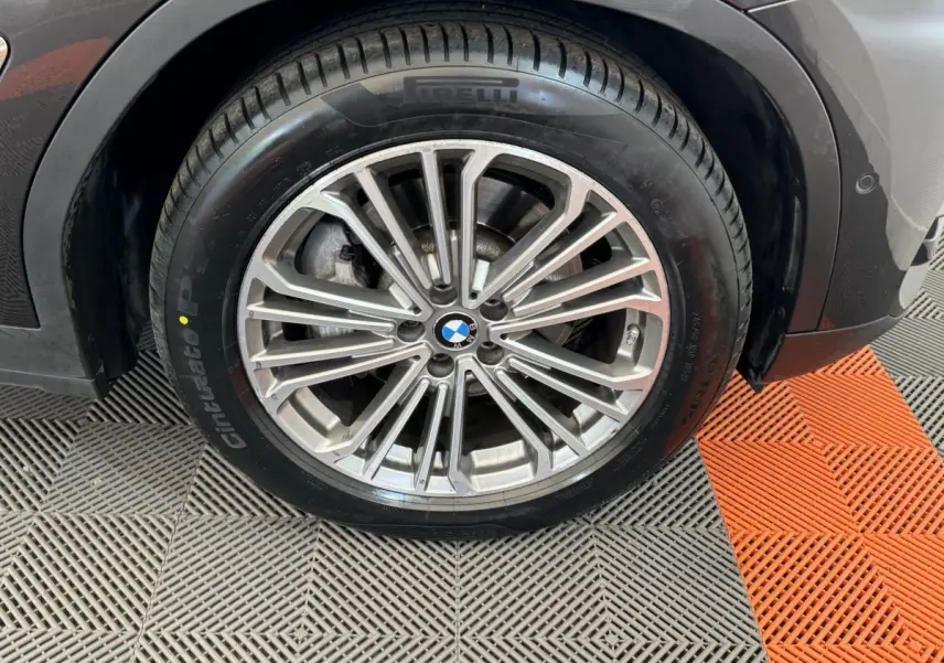 Gros plan sur la roue avant droite d’un BMW X3 gris foncé, avec jante alliage et pneu Pirelli Cinturato.