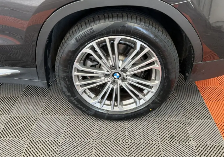 Gros plan sur la roue avant droite d’un BMW X3 gris foncé avec jante alliage multi-branches et pneu Pirelli.