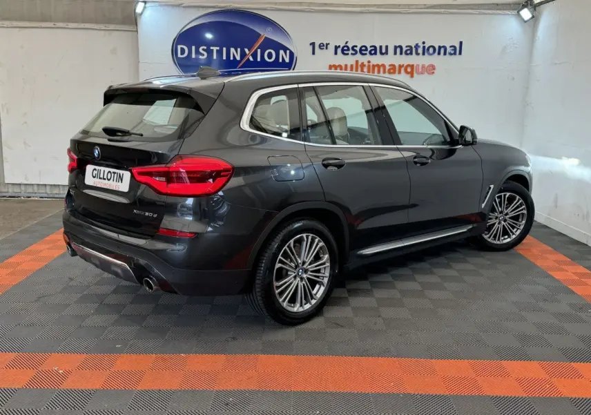 BMW X3 xDrive30d gris foncé vu en 3/4 arrière droit, avec jantes alliage et feux arrière LED visibles