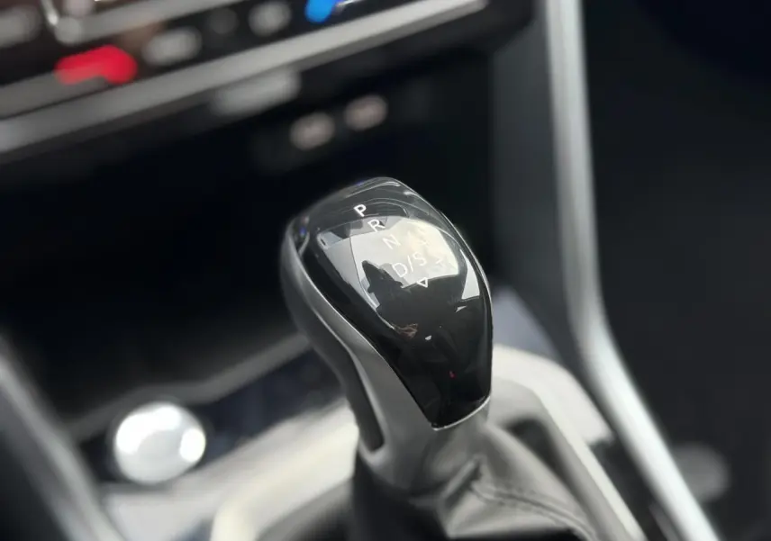 Le levier de vitesses automatique noir brillant du Volkswagen T-Roc 1.5 TSI 150 DSG Life 30 Years, intérieur moderne.