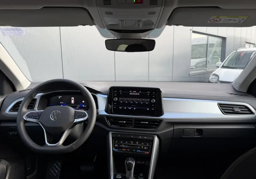Vue intérieure avant du Volkswagen T-Roc 1.5 TSI 150 DSG Life 30 Years avec tableau de bord noir et écran tactile central.