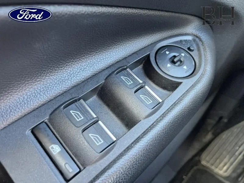 Gros plan sur les commandes de lève-vitres et réglage des rétroviseurs côté conducteur du Ford Kuga blanc Glacier 2018.