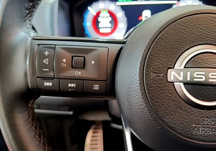 Gros plan sur le volant en cuir noir du Nissan Qashqai e-Power 2023 avec commandes multifonctions et tableau de bord numérique.