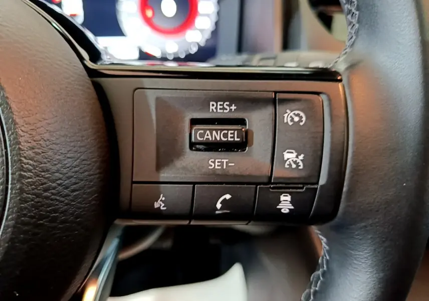 Gros plan sur les commandes multifonctions en cuir et alu du volant noir du Nissan Qashqai e-Power 2023.