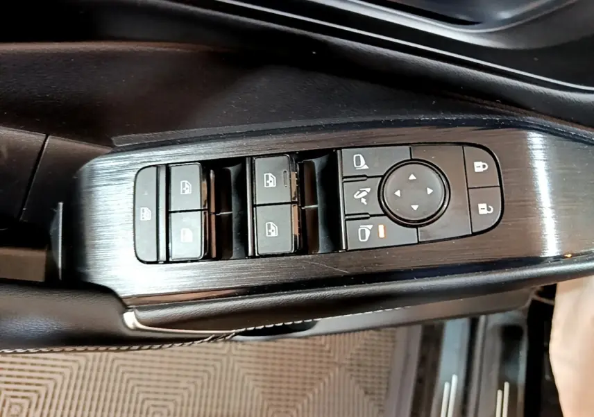 Gros plan sur la commande des vitres et rétroviseurs côté gauche du Nissan Qashqai e-Power noir, finition alu brossé.