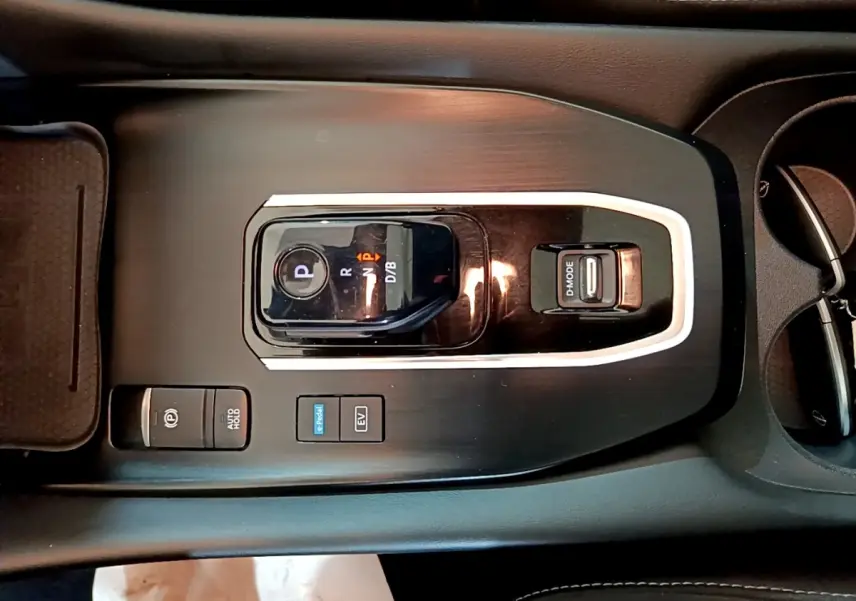 Vue plongeante sur la console centrale noire du Nissan Qashqai e-Power 2023 avec sélecteur de vitesse et boutons de mode.