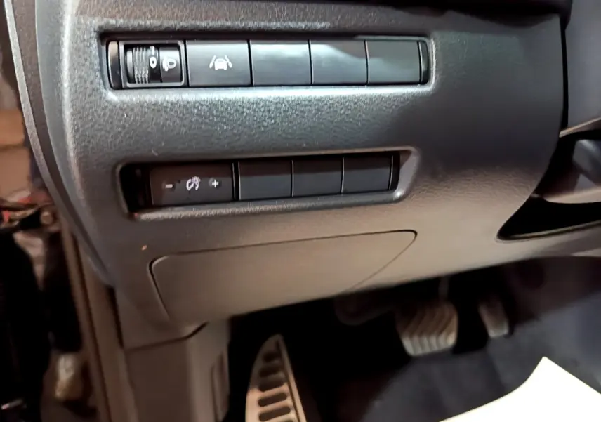 Détail du tableau de bord côté gauche avec commandes d'aide à la conduite et pédales visibles dans un Nissan Qashqai noir.