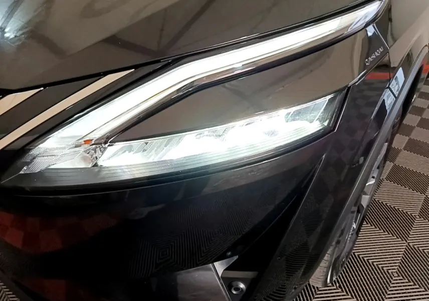 Gros plan sur le phare avant gauche allumé du Nissan Qashqai e-Power noir, soulignant ses lignes modernes et LED.