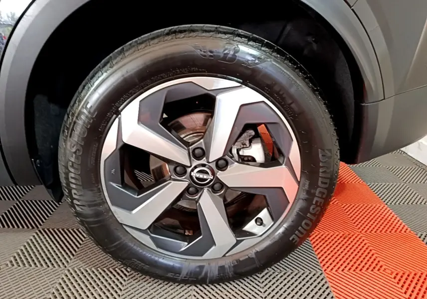 Gros plan sur la roue avant droite du Nissan Qashqai noir, jante alliage à design géométrique et pneu Bridgestone.