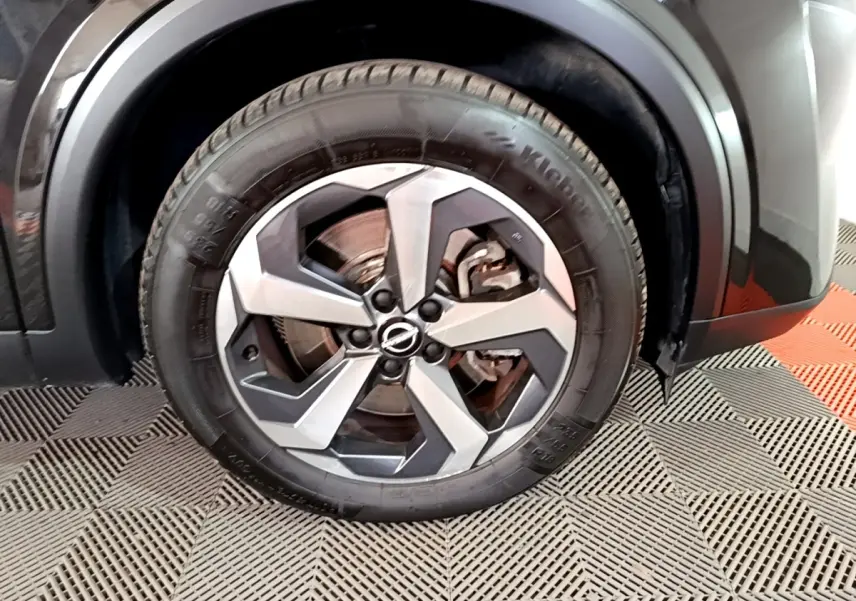 Gros plan sur la roue avant droite du Nissan Qashqai noir, mettant en valeur la jante alu bicolore au design moderne.