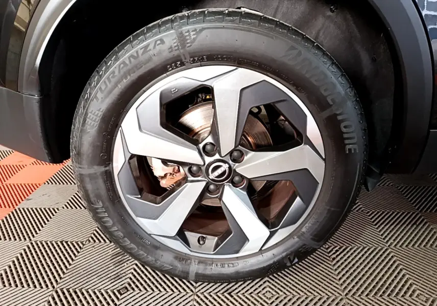 Gros plan sur la roue avant droite noire du Nissan Qashqai e-Power 190 N-Connecta avec jante alu bicolore.