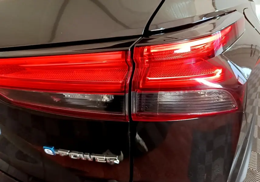 Gros plan sur le feu arrière droit rouge et blanc d’un Nissan Qashqai e-Power noir, avec logo e-Power visible.