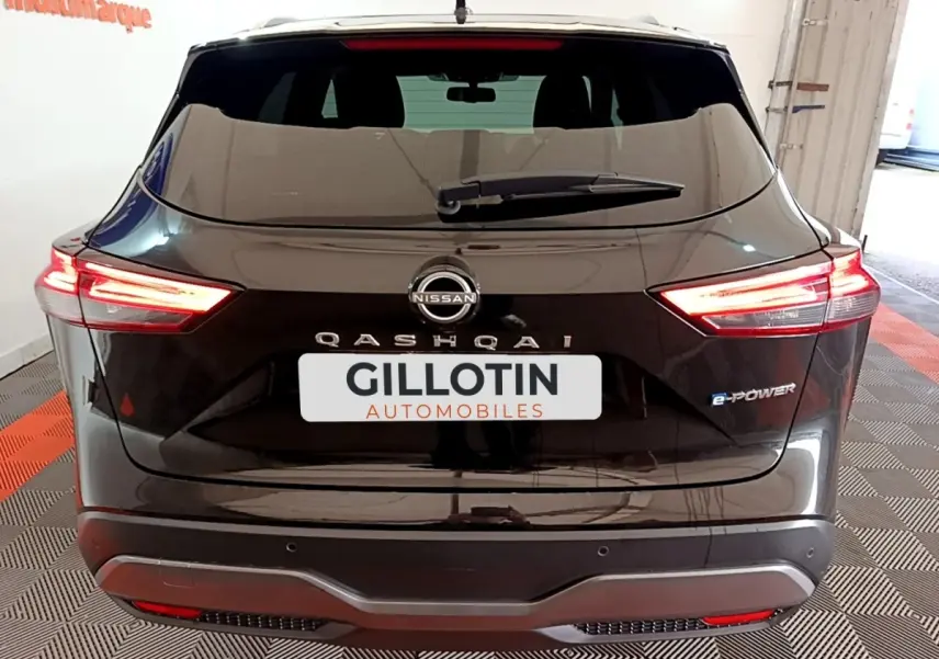 Vue arrière d'un Nissan Qashqai e-Power noir avec feux LED allumés et logo e-Power visible à droite.