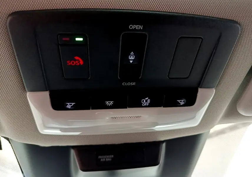 Vue en plongée sur le panneau de commandes de toit intérieur du Nissan Qashqai e-Power noir, avec bouton SOS rouge allumé.