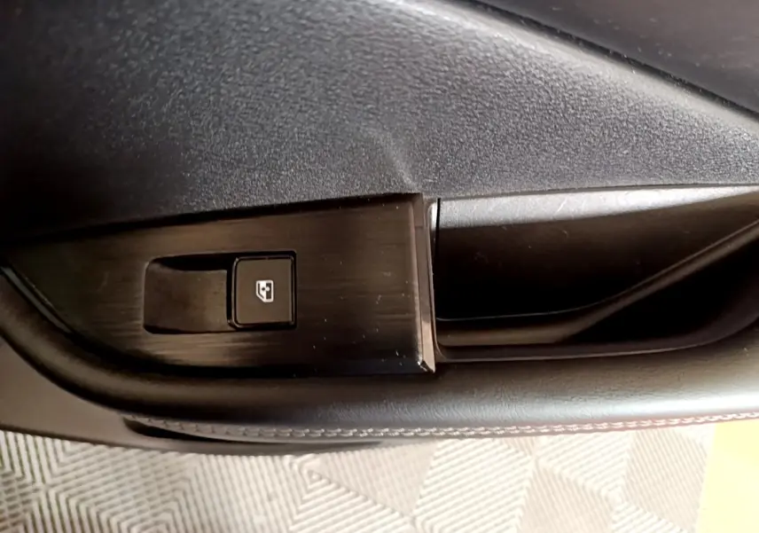 Gros plan sur le bouton de verrouillage de fenêtre côté conducteur du Nissan Qashqai e-Power noir 2023.