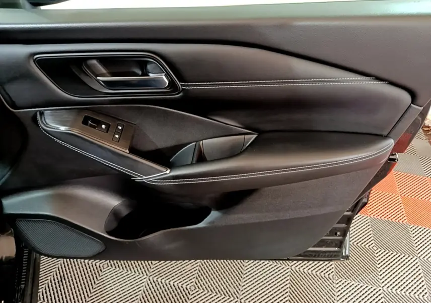 Gros plan sur la porte intérieure côté gauche du Nissan Qashqai e-Power 190 N-Connecta noire avec surpiqûres blanches et commandes électriques.