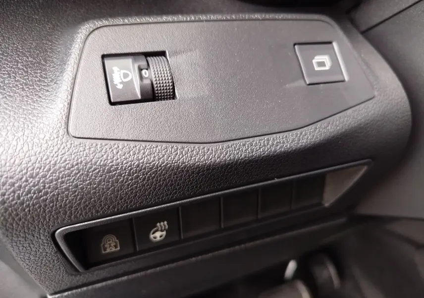Détail intérieur sur les commandes noires en plastique texturé du tableau de bord du Citroën Berlingo Kaolin White 2025.