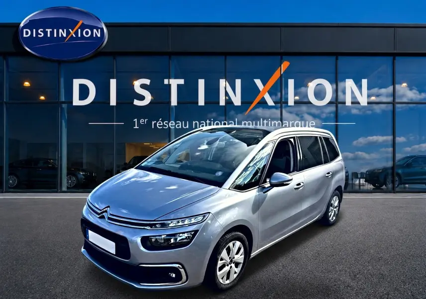 Citroën Grand C4 Spacetourer gris alu, vue 3/4 avant droit devant un showroom Distinxion.