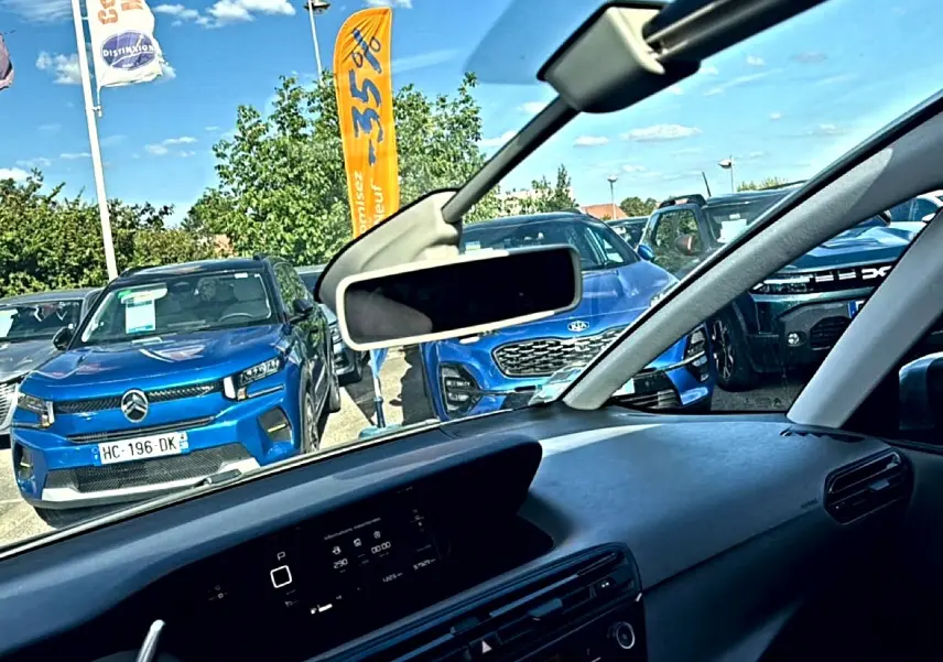 Vue intérieure côté conducteur du tableau de bord du Citroën Grand C4 SpaceTourer gris alu avec rétroviseur central visible.