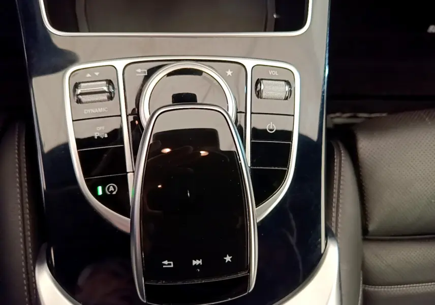 Gros plan sur la console centrale noire brillante de la Mercedes Classe C Coupé C 220 d Fascination 2018 avec commandes tactiles et molette.