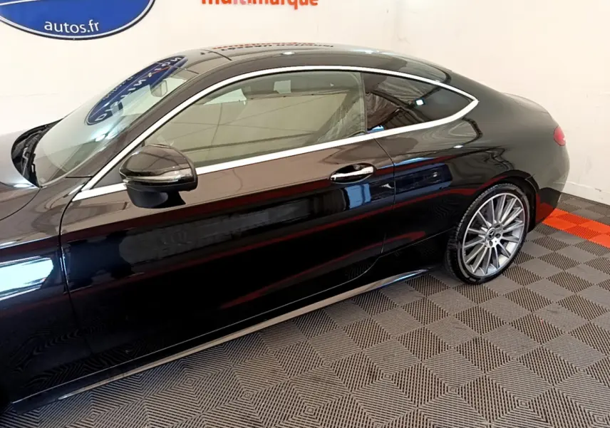 Vue latérale côté gauche d'une Mercedes Classe C Coupé noire brillante, mettant en valeur ses jantes alliage et sa ligne élégante.