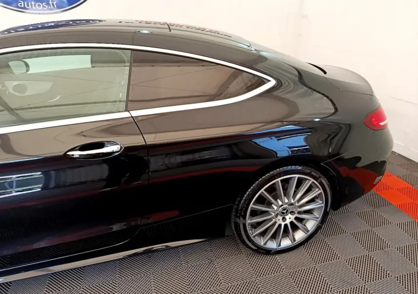 Vue latérale côté droit d'une Mercedes Classe C Coupé noire, mettant en valeur la jante alliage et la ligne fluide du toit.