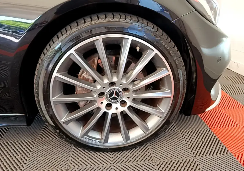 Gros plan sur la roue arrière droite d'une Mercedes Classe C Coupé noire avec jante alliage multibranches.