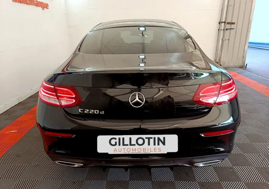 Vue arrière d'une Mercedes Classe C Coupé C 220 d noire avec feux LED allumés dans un garage.