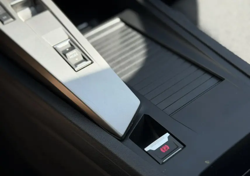 Gros plan sur la console centrale intérieure de la Peugeot 308 gris Artense, avec frein de parking électrique et bouton Drive Mode.